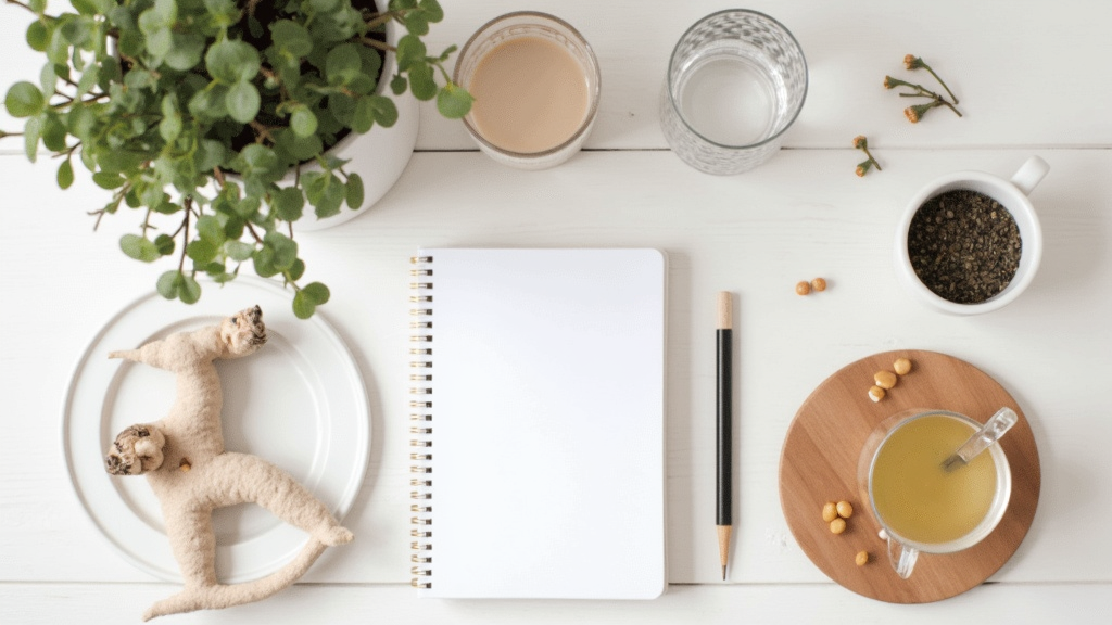 Pregnancy essentials flat lay including a journal, supplements, and soothing herbal tea.